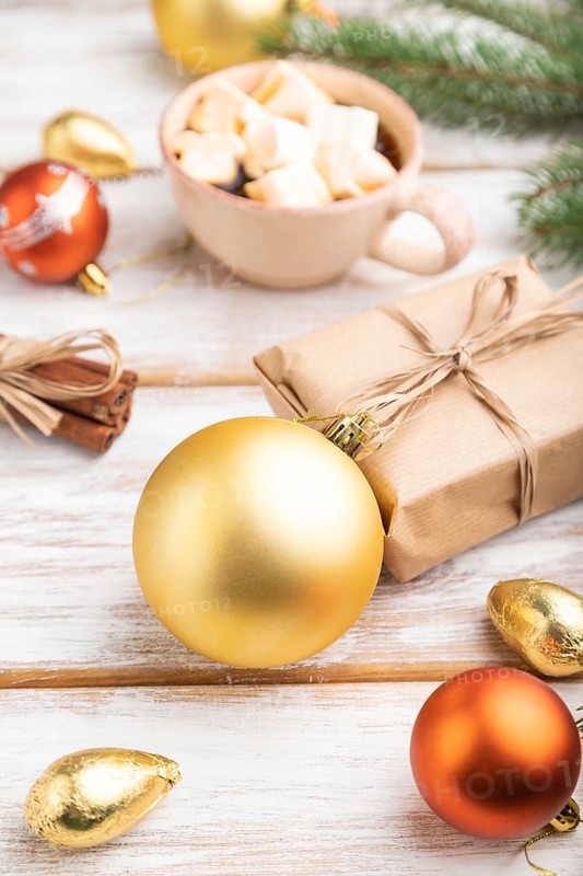 Christmas or New Year composition. Decorations, box, golden balls, cinnamon, fir and spruce branches, cup of coffee, on a white wooden background. Side view, close up, selective focus