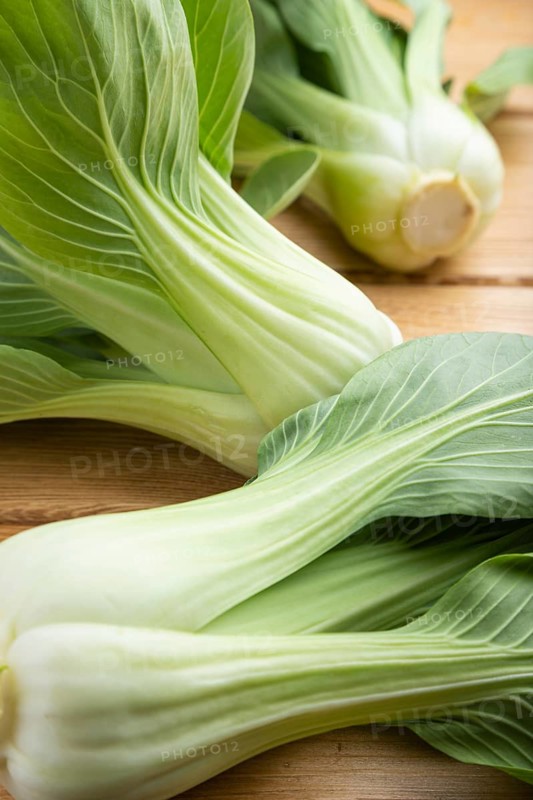 Fresh green bok choy or pac choi chinese cabbage on a brown wooden background. Side view, close up