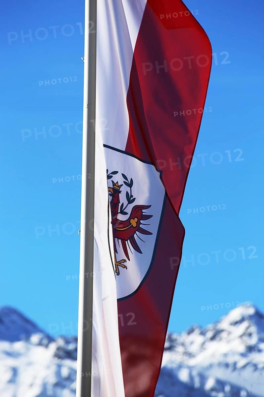 Österreichische Flagge mit schneebeckten Bergen im Hintergrund (Austrian flag with snow-covered mountains in the background)