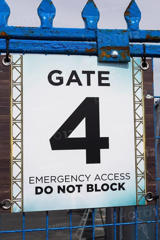 Close-up of posted emergency access gate 4 Do Not Block notice sign on blue painted steel and wire mesh security fence, Old Montreal, Quebec, Canada, North America