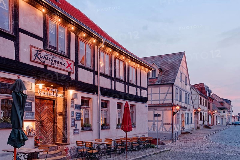A festively illuminated restaurant in the evening and half-timbered houses in the cobbled Kirchstraße in the old town of Tangermünde, Hanseatic town in the Altmark. Saxony-Anhalt, Germany, Europe