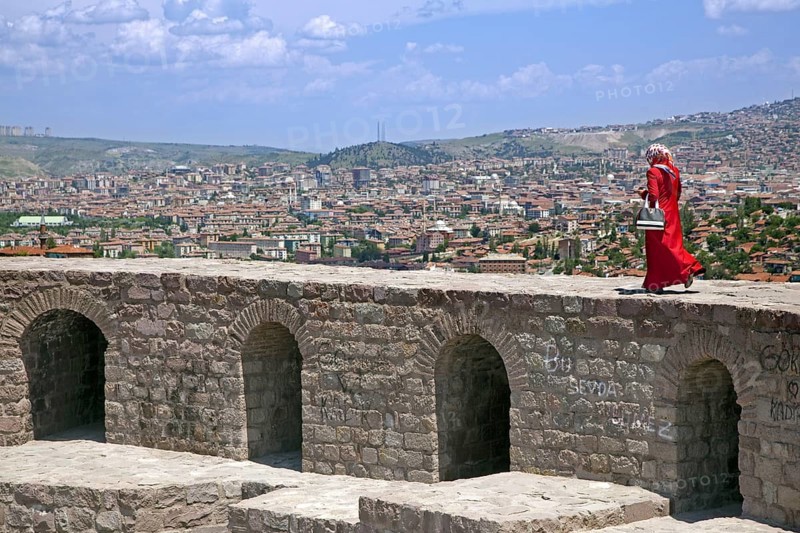 Muslim woman dressed in Turkish Hijab style walking on the old citadel wall with view over the city Ankara, Turkey, Asia
