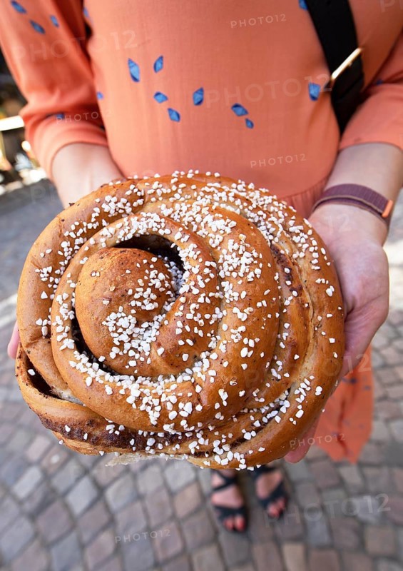 Women's hands with a traditional cinnamon bun, Haga neighbourhood, Gothenburg, Västra Götalands län province, Sweden, Europe