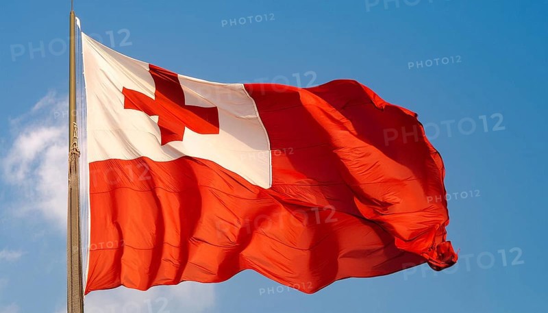 The flag of Tonga, Pacific island state, flutters in the wind, isolated against a blue sky
