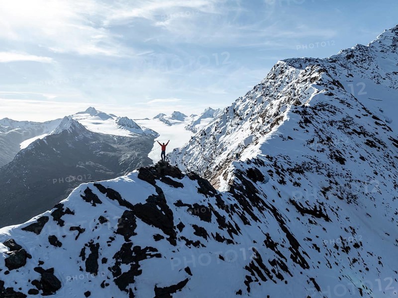 Mountaineer standing triumphantly on the snow-covered Ramoljoch under a clear sky in the Alps, Gurgler Ferner glacier in the background, Obergurgl, Ötztal Alps, Tyrol, Austria, Europe