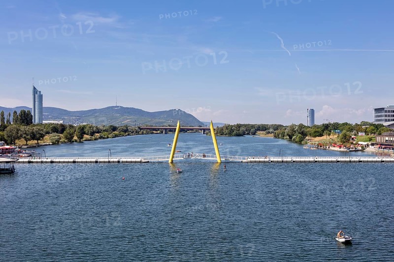 View of a river with bridge, surrounded by mountains and architecture, Vienna