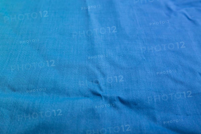 Fragment of smooth cotton blue tissue. Side view, natural textile background and texture