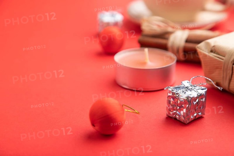 Christmas or New Year composition. Decorations, box, cinnamon, fir and spruce branches, cup of coffee, on a red paper background. Side view, copy space, selective focus