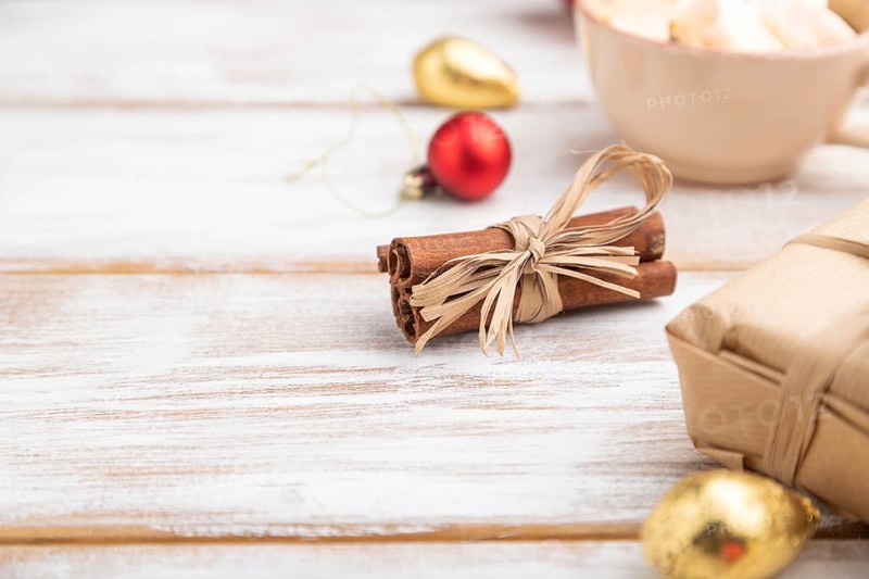 Christmas or New Year composition. Decorations, box, red balls, cinnamon, fir and spruce branches, cup of coffee, on a white wooden background. Side view, copy space, selective focus