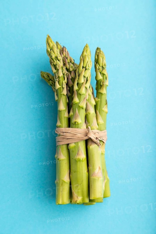 Bunch of fresh green asparagus on blue pastel background. Top view, flat lay, close up. harvest, healthy, vegan food, concept, minimalism