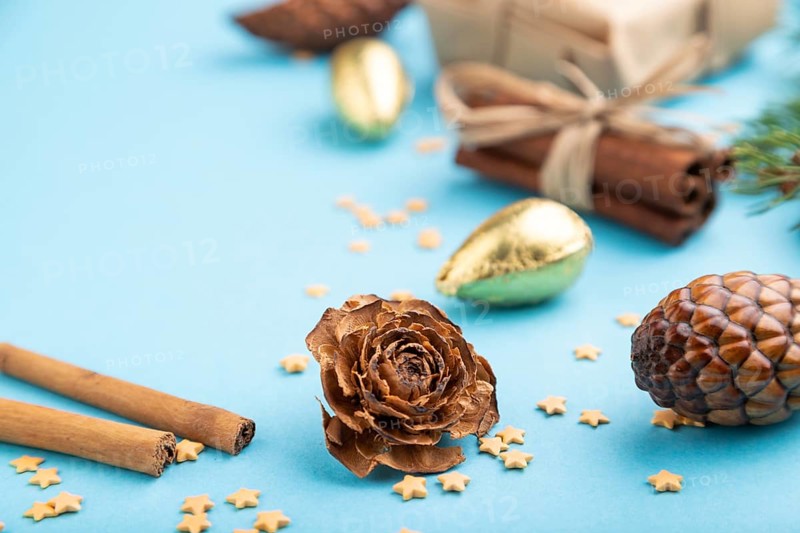 Christmas or New Year composition. Decorations, box, cinnamon, cones, fir and spruce branches, on a blue paper background. Side view, close up, selective focus