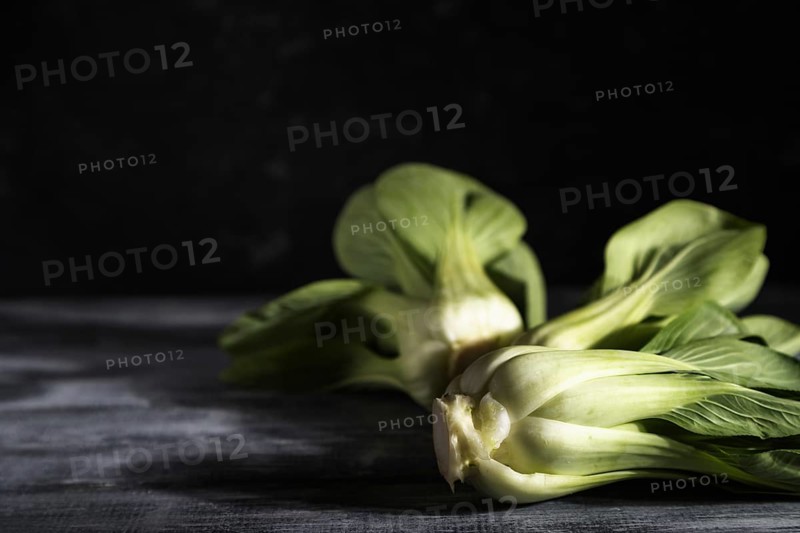 Fresh green bok choy or pac choi chinese cabbage on a gray wooden background. Hard light, contrast, dark, moody. Side view, copy space, selective focus