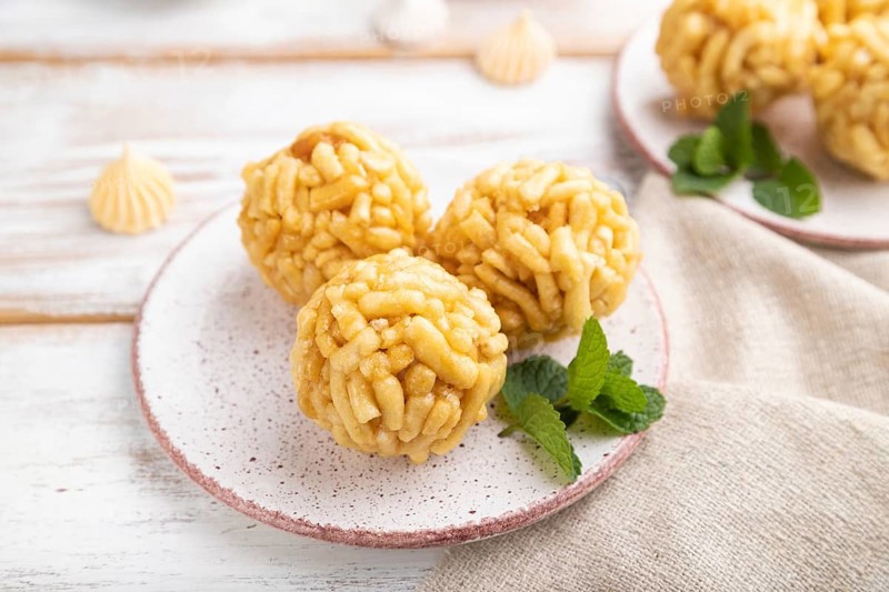 Traditional Tatar candy chak-chak made of dough and honey with cup of coffee on a white wooden background and linen textile. Side view, close up, selective focus