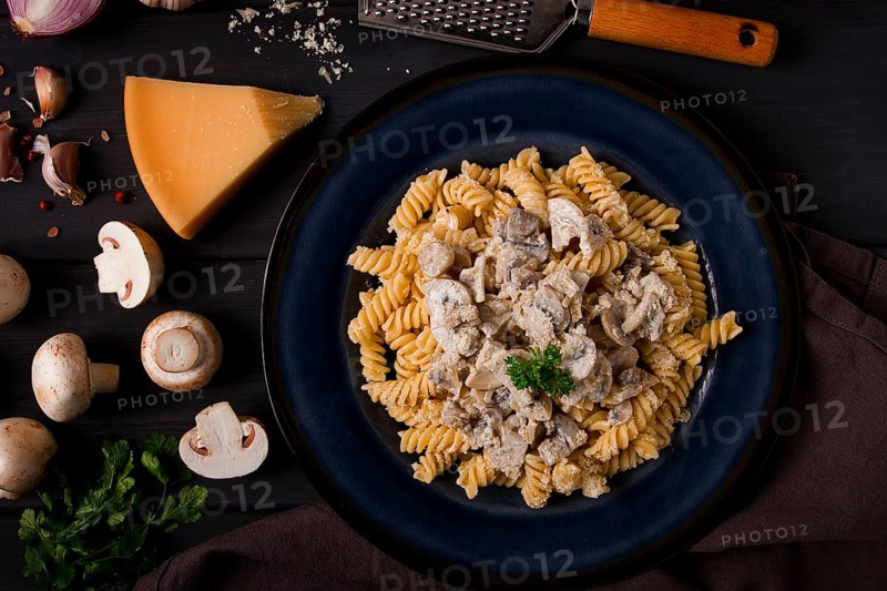 Fusilli pasta, with champignons in cream sauce, top view, with ingredients, on a wooden table, no people
