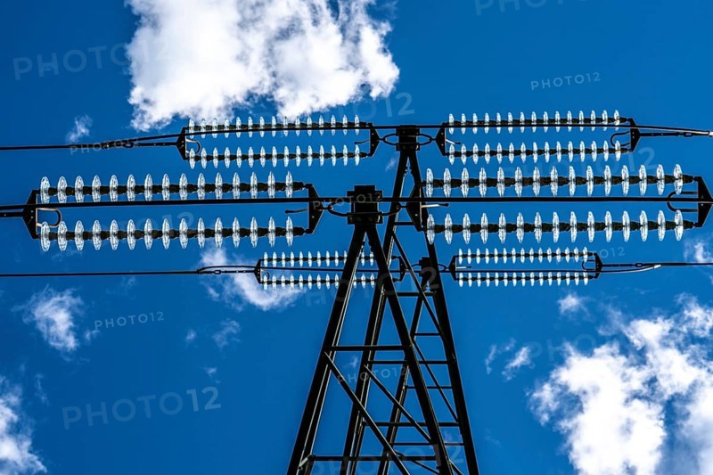 Insulators made of glass on a high-voltage line, they hang on the pylons as a suspension device between the pylon and the live, non-insulated cable, extra-high voltage line, symbolic image energy