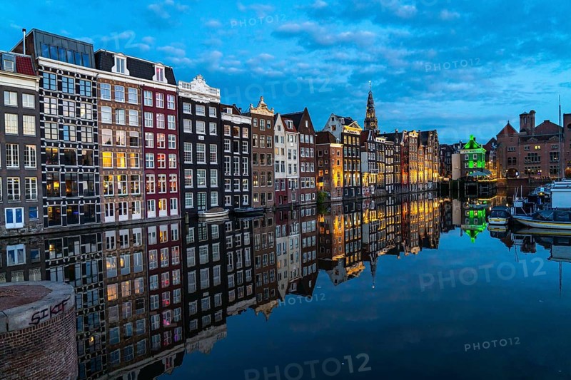 Canal houses on the Damrak, in the centre of the old town of Amsterdam, harbour, starting point of many canal tours, in the evening, church tower of the Oude Kerk, Netherlands