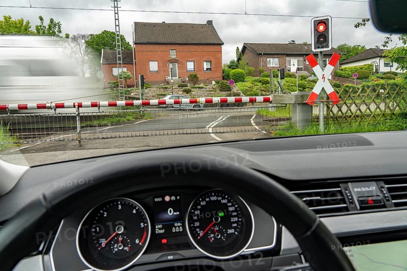 Car waiting at a level crossing, closed barriers, red warning light, traffic light and St Andrew's cross, RRX, Rhein-Ruhr-Express, National Express passes by, near Geilenkirchen North Rhine-Westphalia, Germany, Europe