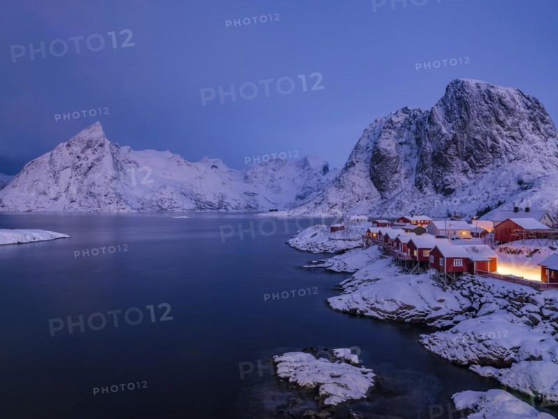 Rorbuer huts of Hamnoy at the fjord at dusk, snowy mountains in the background, Hamnøy, Reine, Moskenesøya, Lofoten, Norway, Europe