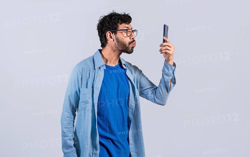 Funny Man blowing kisses on the cell phone isolated. young man taking selfie and blowing kisses on the mobile phone isolated