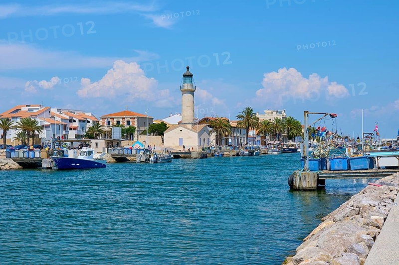 Coastal town with colourful houses and palm trees, boats in the water and a lighthouse, on a sunny day, summer, Le Grau-du-Roi, Gard, Mediterranean Sea, France, Europe