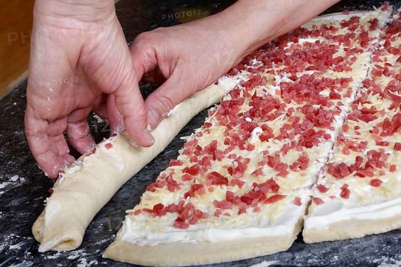 Swabian cuisine, preparation of savoury yeast plait with smoked meat, salty wreath bread, yeast yeast dough pastries, roll up raw yeast dough with bacon cubes, grated cheese, sour cream, grandmother's cooking, regional, home cooking, typical Swabian cuisine reinterpreted, traditional cuisine reinterpreted, men's hands, food photography, studio, Germany, Europe