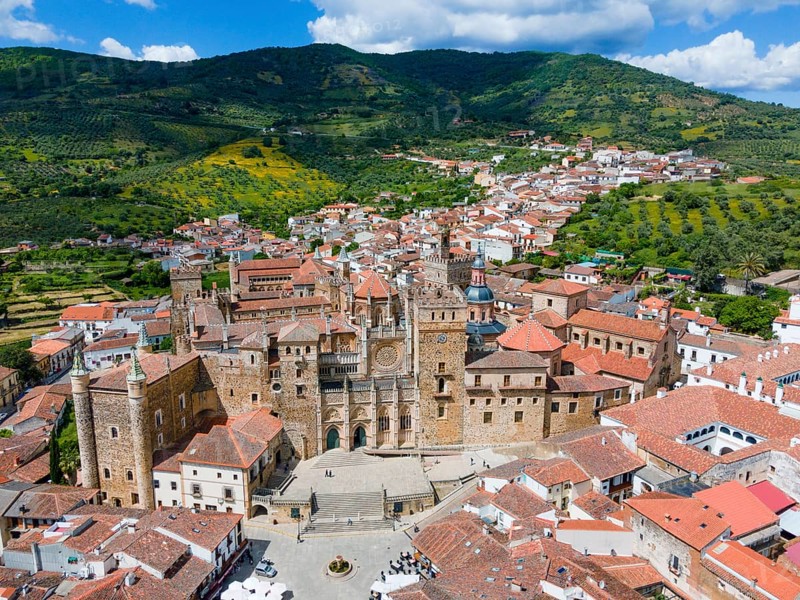 Aerial view of an old monastery with red roofs, surrounding mountains and green hills, depicted in a historical environment in Spain, aerial view, pilgrimage church and monastery, Real Monasterio de Nuestra Señora de Guadalupe, Guadalupe, Cáceres province, Caceres, Extremadura, Spain, Europe