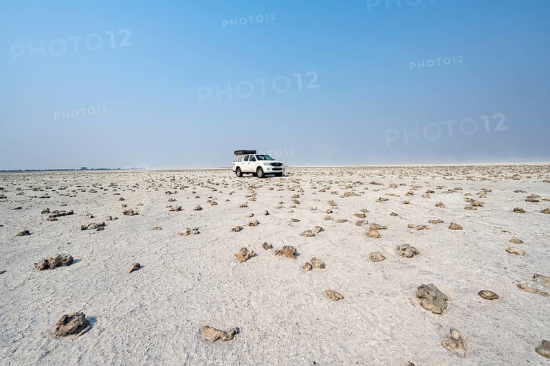 Four-wheel drive Toyota Hilux with roof tent, driving over salt pan, lone car in large wide plain, Nxai Pan National Park, Botswana, Africa