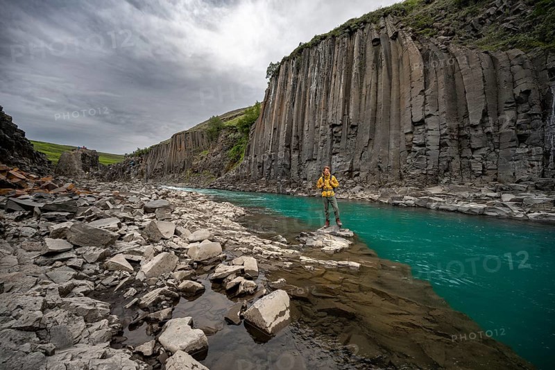 Tourist standing by the river in Stuðlagil Canyon, turquoise blue river between basalt columns, Egilsstadir, Iceland, Europe