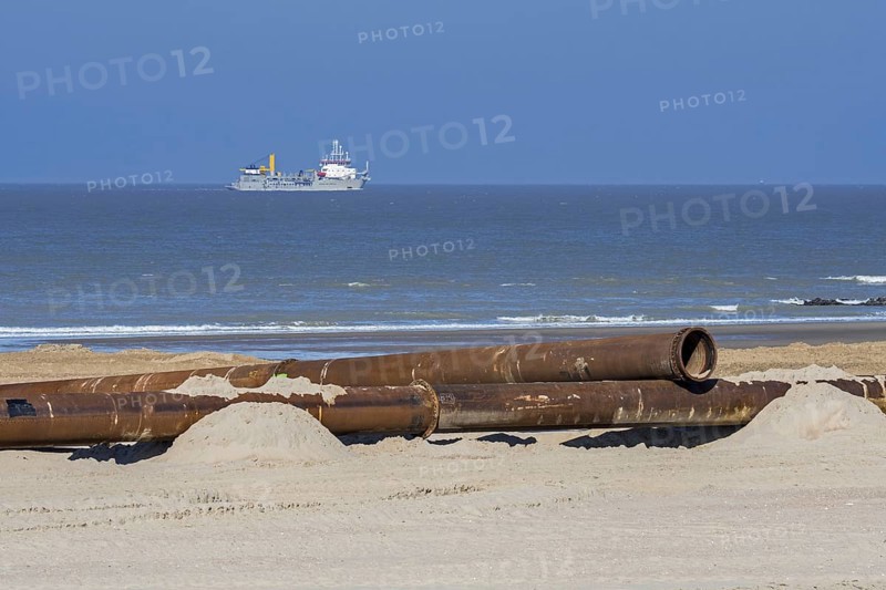 Trailing suction hopper dredger at sea and pipeline for sand replenishment, beach nourishment to reduce storm damage along the Belgian coast