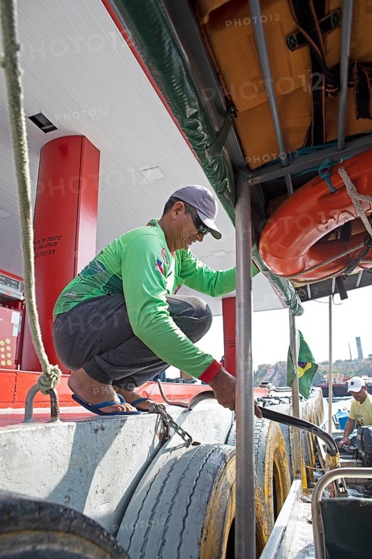 Brazilian man refuelling a boat from a floating petrol station on the Rio Negro, Manaus, Amazonas state, Brazil, South America