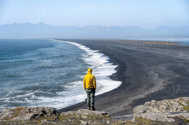Tourist looking over long black sand beach, Reynisfjara Beach, South Iceland, Iceland, Europe