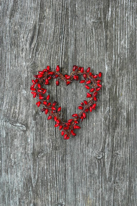 Heart-shaped rosehip wreath on wooden door