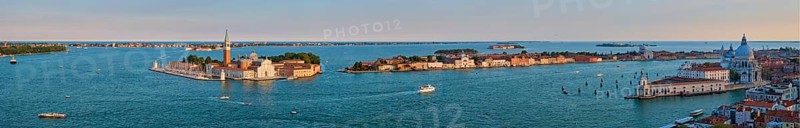 Panorama of Venice lagoon and San Giorgio di Maggiore church and Santa Maria della Salute with boats and vaporetto on sunset from St Mark's Campanile bell tower, Venice, Italy. Camera horizontal pan