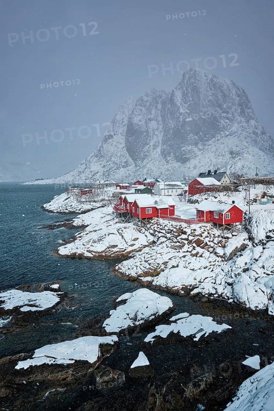 Iconic Hamnoy fishing village on Lofoten Islands, Norway with red rorbu houses. With falling snow in winter