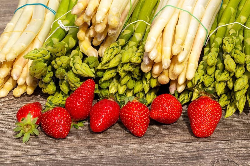Green asparagus, white asparagus and fresh strawberries decorated on a rustic wooden table