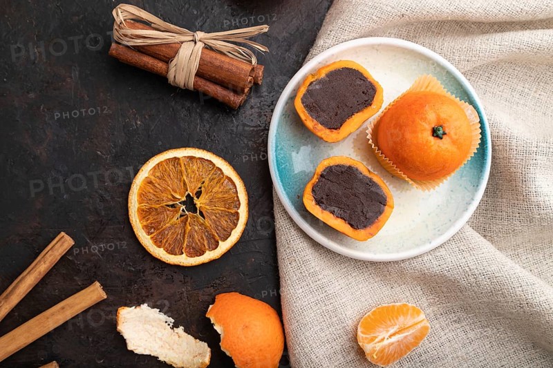 Truffle chocolate tangerine candies on a black concrete background and linen textile. top view, flat lay, close up