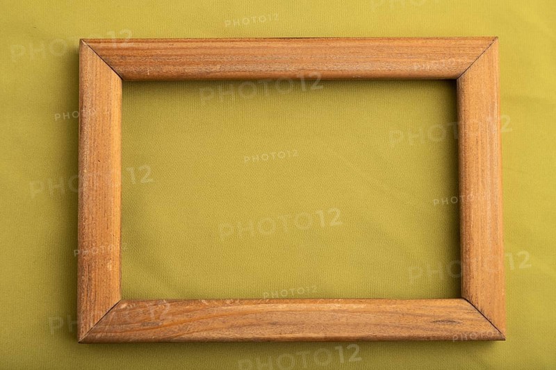 Wooden frame on smooth green olive silk tissue. Top view, flat lay, natural textile background and texture