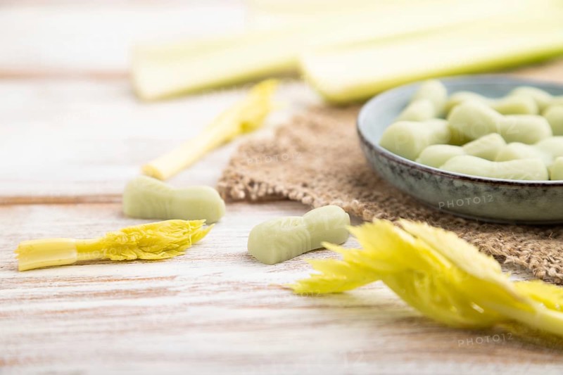 Jelly celery candies on white wooden background and linen textile. close up, side view, selective focus