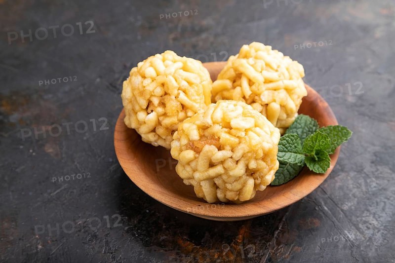 Traditional Tatar candy chak-chak made of dough and honey in wooden plate on a black concrete background. Side view, close up