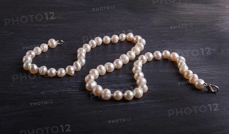Caramel colored pearl beads on a black background. top view, close up