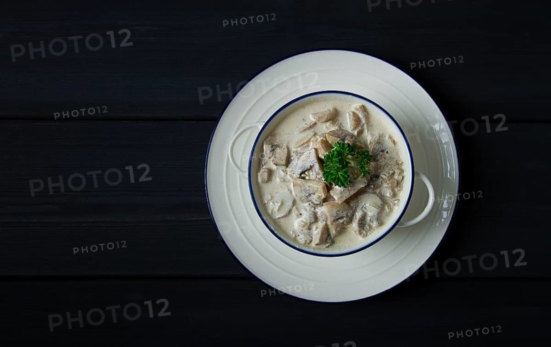 Cream sauce with mushrooms, top view, on a dark gray wooden table, horizontal, no people