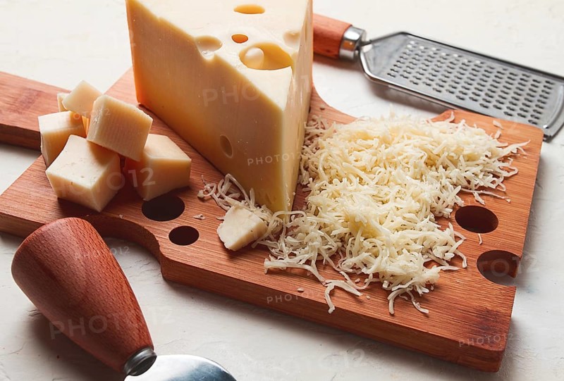 Grated cheese, Maasdam, on a cutting board, grater and cheese knife, close-up, no people