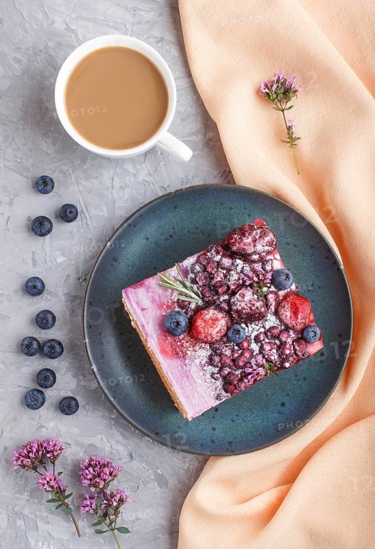Berry cake with milk cream and blueberry jam on blue ceramic plate with cup of coffee and fresh blueberries on a gray concrete background with orange textile. top view, flat lay, close up