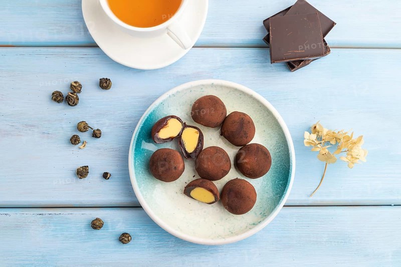 Japanese rice sweet buns chocolate mochi filled with cream and cup of green tea on blue wooden background. top view, flat lay, close up