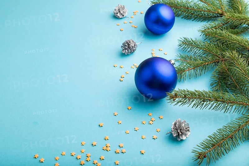 Christmas or New Year composition. Decorations, blue balls, cones, fir and spruce branches, on a blue paper background. Side view, copy space