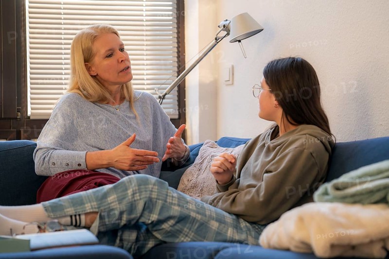 Mother and daughter, teenage, 13 years old, in a confidential conversation, at home