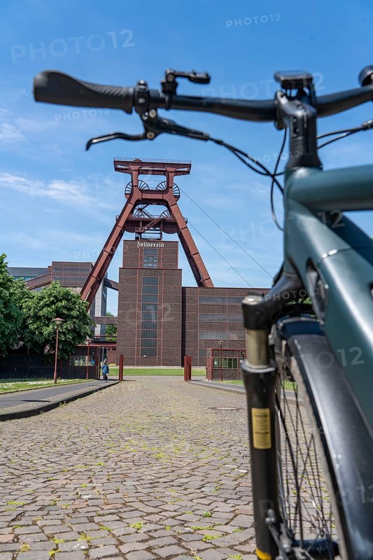 Cycling in the Ruhr region, by bike, e-bike, at the Zollverein Coal Mine Industrial Complex World Heritage Site, double trestle winding tower shaft XII, Essen, North Rhine-Westphalia, Germany, Europe