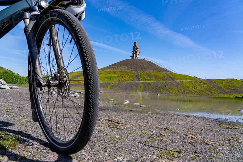 Cyclist on the Rheinelbe spoil tip in Gelsenkirchen, 100 metre high spoil tip, landscape park, with the sculpture Himmelsleiter, made of concrete parts of the former Rheinelbe colliery, Gelsenkirchen, North Rhine-Westphalia, Germany, Europe