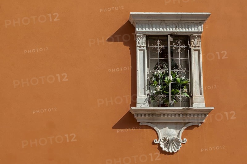 Small house altar with lattice and flowers on an orange-coloured house facade, Venice, Italy, Europe