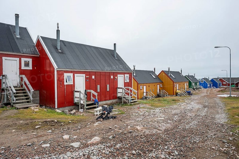Row of colourful houses along a gravel road under a cloudy sky, remote Arctic Inuit settlement Ittoqqortoormiit, Scoresbysund or Scoresby Sund or Greenlandic Kangertittivaq, East Greenland, Greenland, North America